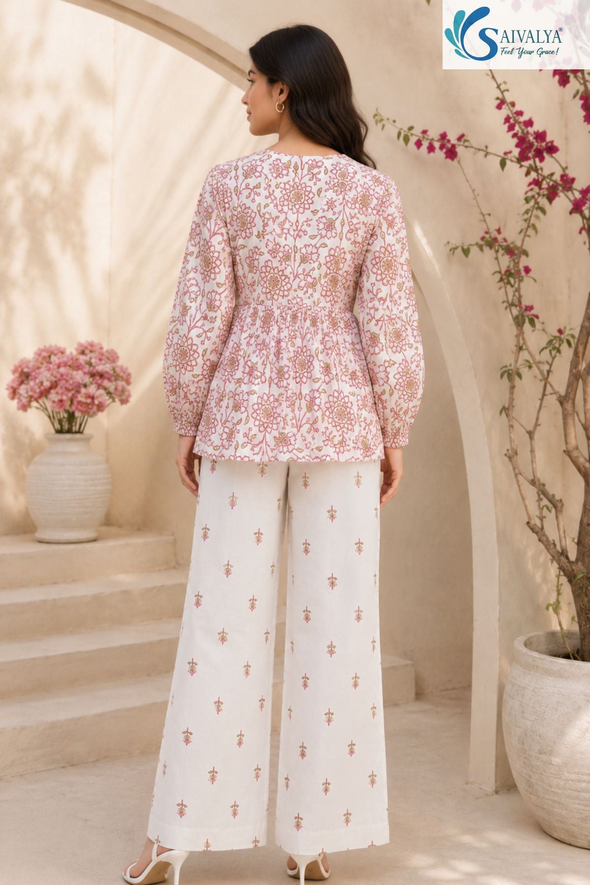 Back view of Bloom & Breezy Peplum Co-ord Set featuring floral printed peplum top with full sleeves and white straight palazzo pants for women ethnic casual wear by Saivalya.