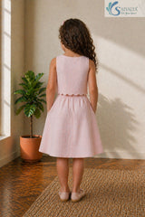 Back view of a young girl standing with her hands in her pockets, wearing the Blush Petal Cotton Co-ord set featuring a sleeveless crop top with a scalloped hem and a matching elastic-back A-line skirt.
