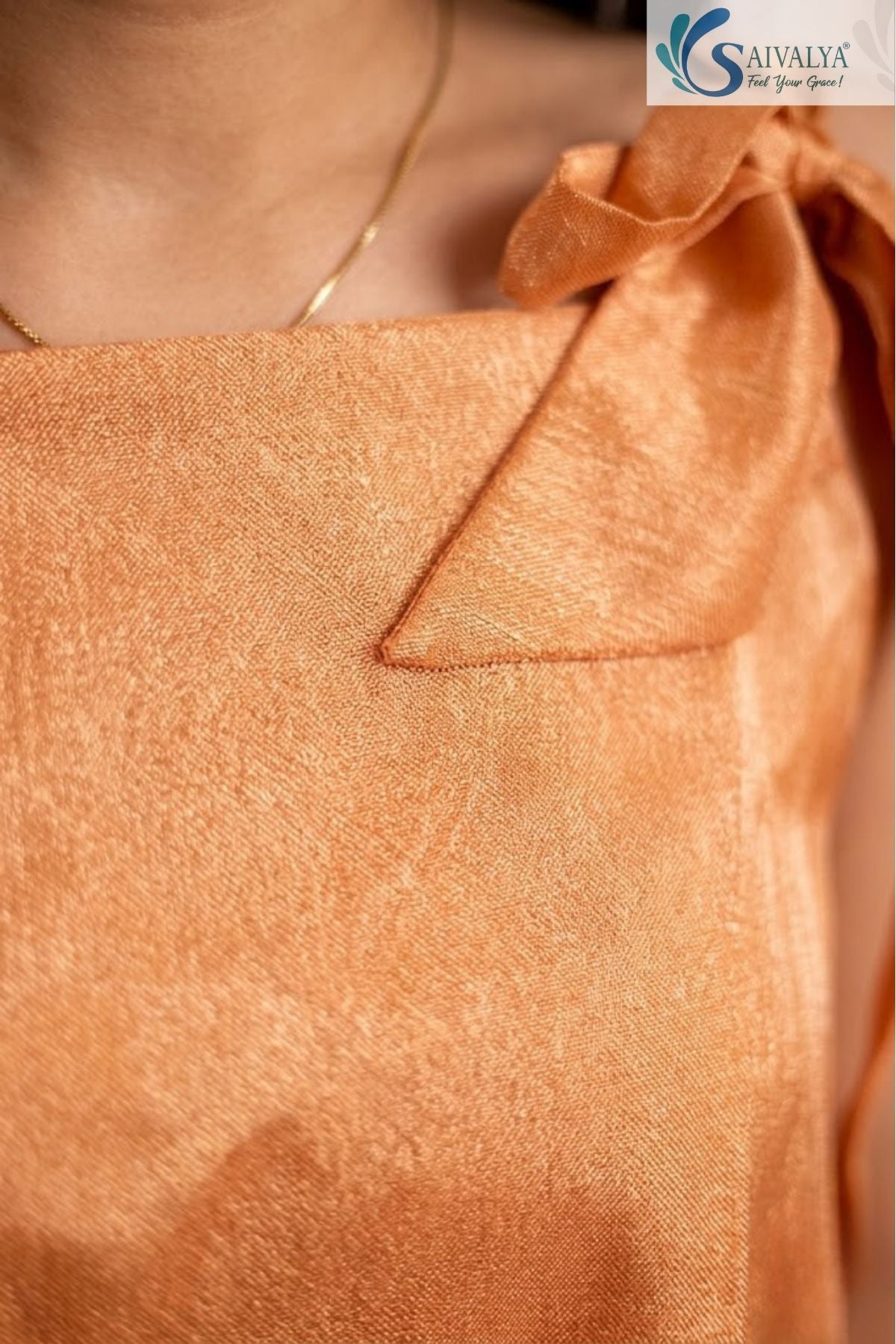 Close up shot of the Saivalya Ojasvi orange shoulder-tie peplum top showcasing the textured fabric and bow strap detail