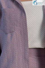 Close-up view highlighting the distinctive puckered, seersucker-style fabric texture of the dusty lavender button-up shirt and matching shorts, layered over a white textured knit crop top.