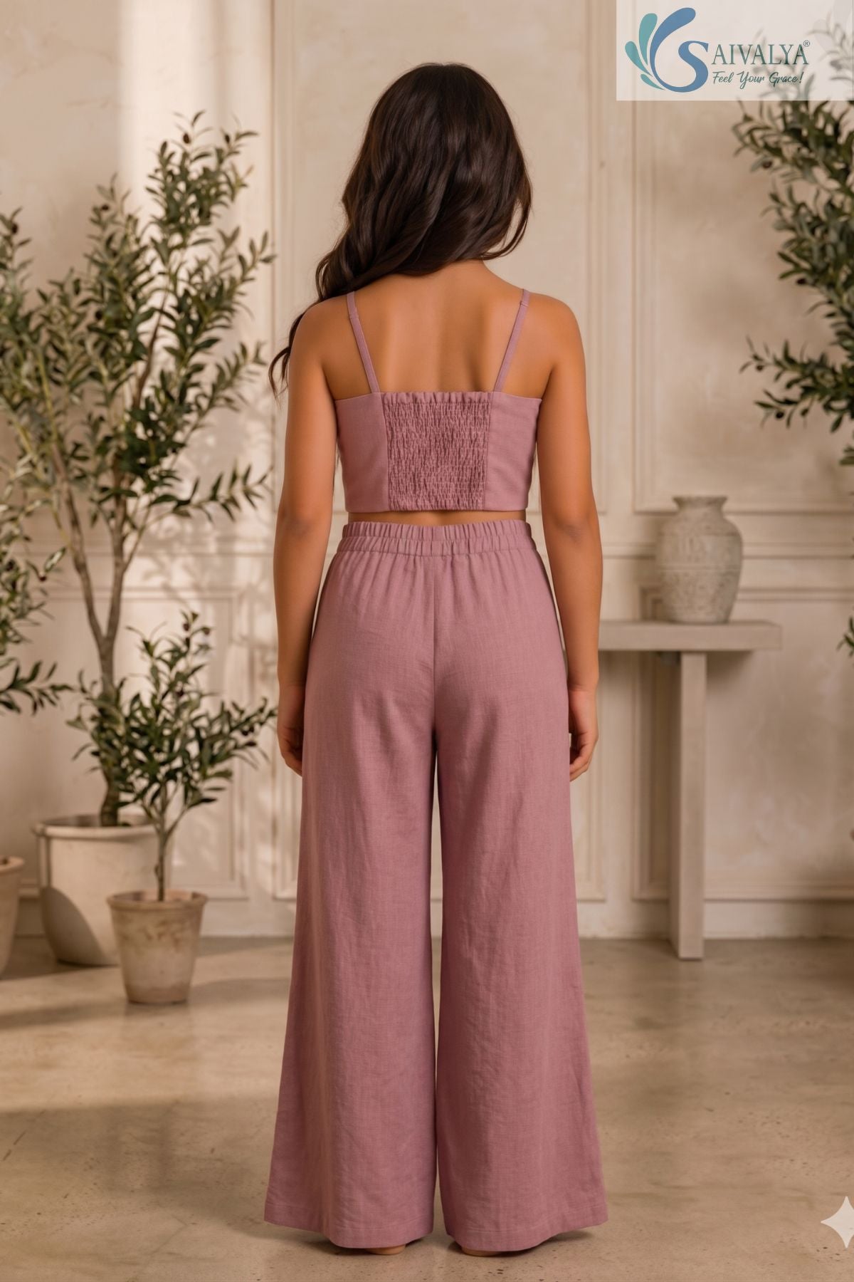 Back view of a young girl wearing the Rose Bloom set without the blazer, showing the mauve pink crop top with a smocked back panel and matching elastic-waist wide-leg trousers.