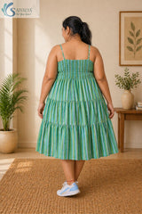 Side view of a woman wearing the Saivalya Verdant Muse green striped tiered midi dress layered over a white top showcasing the flared tiered silhouette and comfortable fit