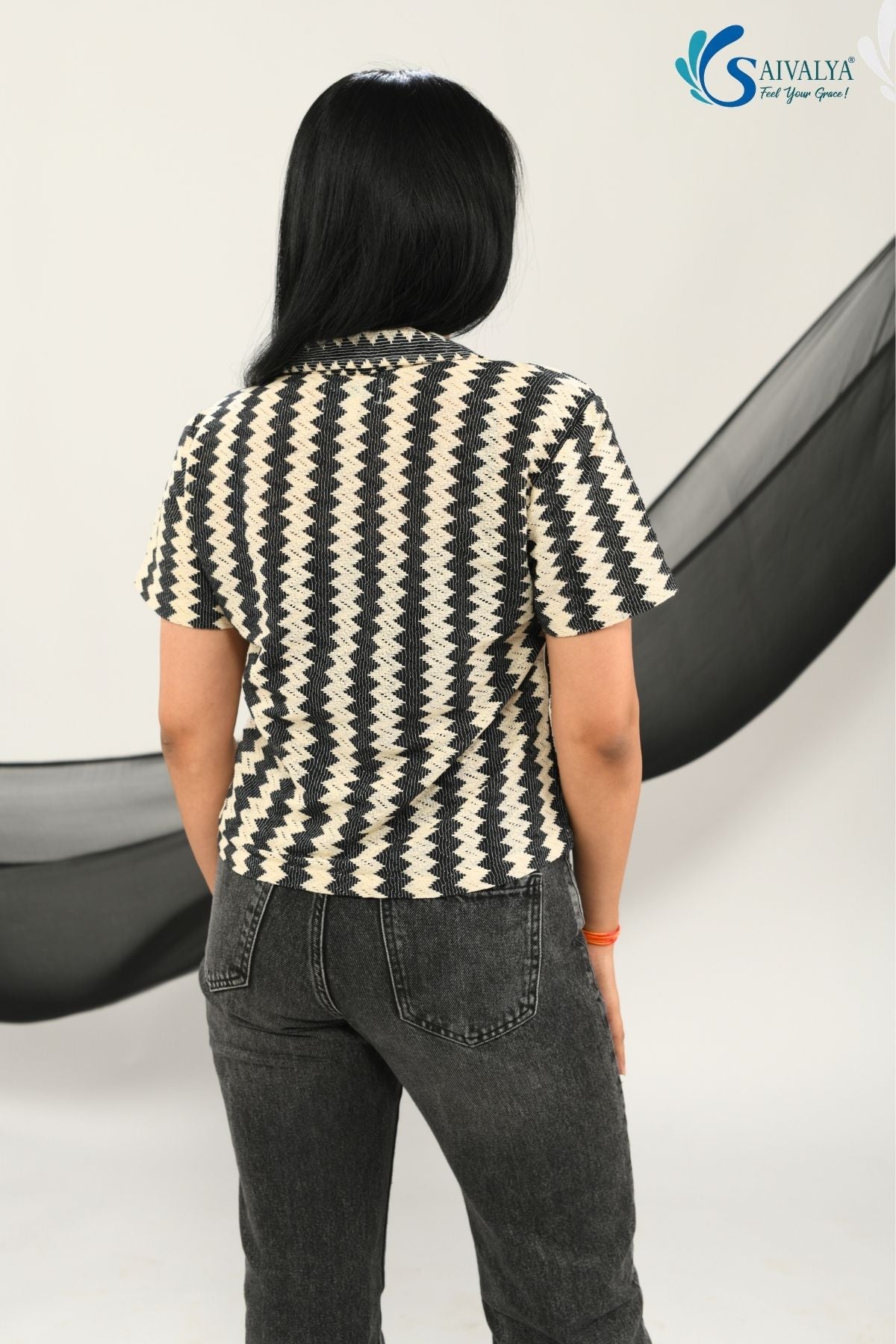 back view of a woman wearing Saivalya black and white vertical chevron print Ottoman jacquard knit top with a polo collar