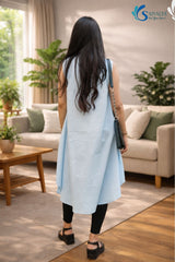 back view of a woman wearing Saivalya's powder sky blue organic cotton sleeveless tunic with a high-low hem and mandarin collar, paired with black leggings.