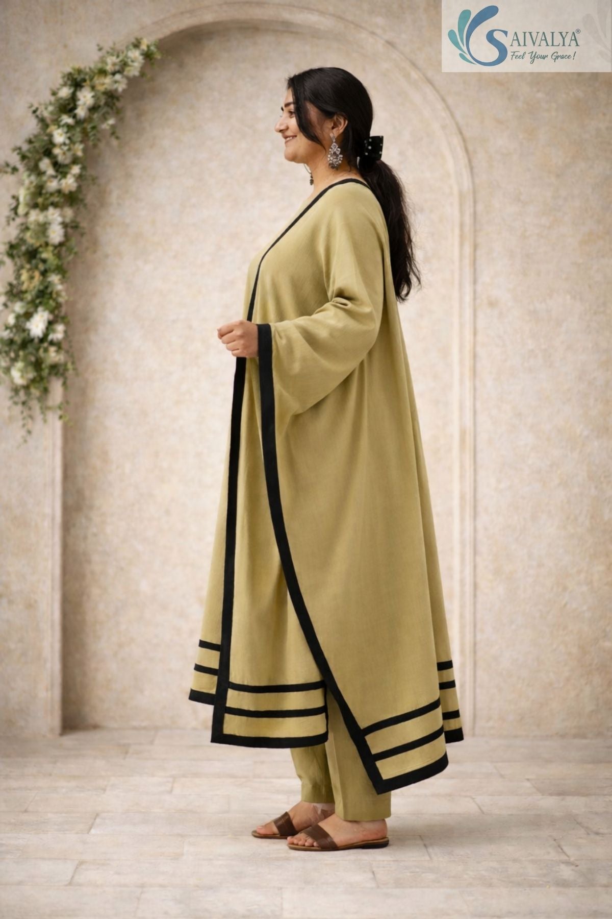 Side view of a woman posing in the Saivalya Olive Zenith Scalloped Suit Set showcasing the draped dupatta with black contrast borders and matching olive trousers