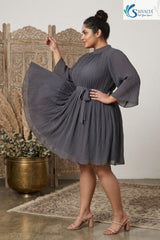 Side profile view of a plus size woman swirling a grey pleated high neck short dress with flare sleeves and a matching fabric belt.