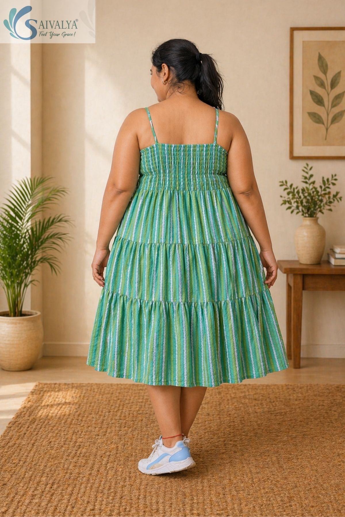 Side view of a woman wearing the Saivalya Verdant Muse green striped tiered midi dress layered over a white top showcasing the flared tiered silhouette and comfortable fit